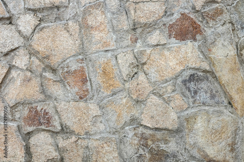 Wall texture of natural chipped stone with cement joints. Decorative stone background.