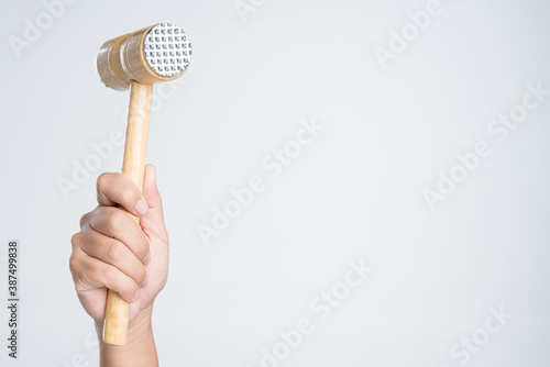 Hand holding meat tenderizer mallet or food hammer photo