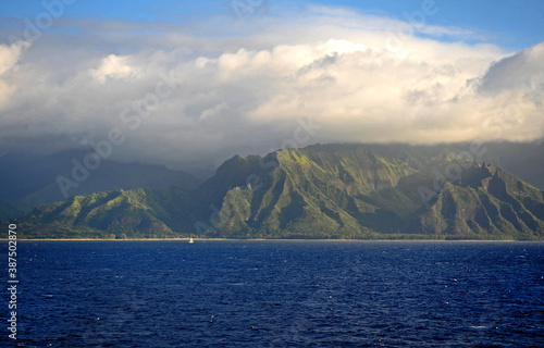 The Napali rugged coastline Hawaii, a small yacht is dwarfed by the dynamic rocky coast. © KRUTOPIMAGES