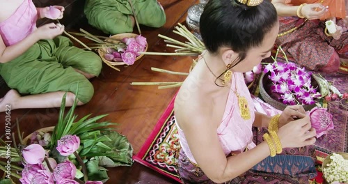 A beautiful asian female dress on Ayutthaya cultural fashion clothes sitting and flower decuration training traditional Thailand tomyam in the vintage old style ancient house photo