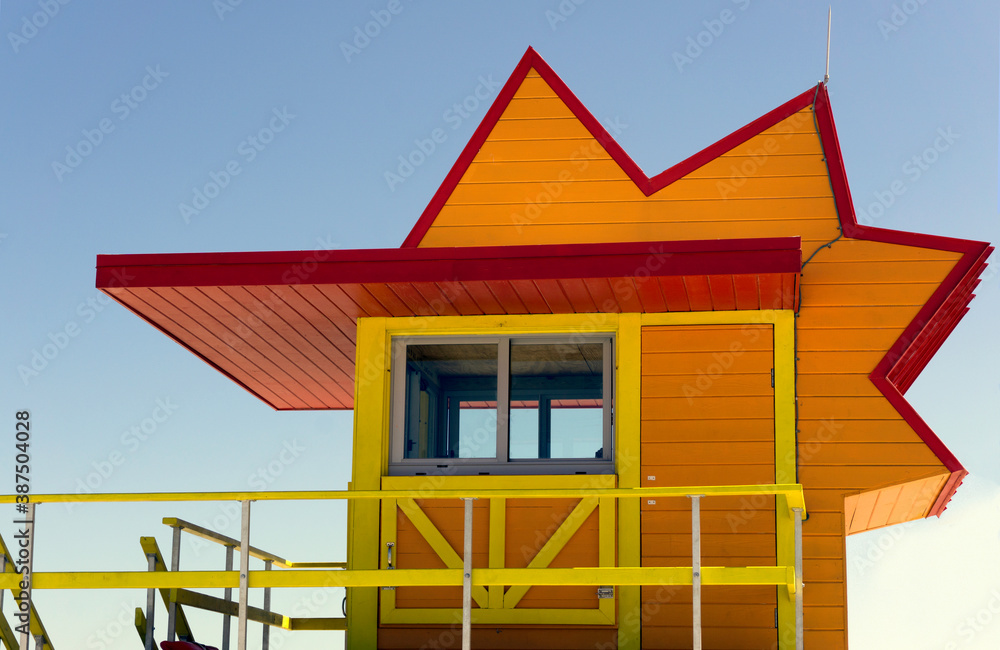 Bright orange life guard station with zigzag roof against a blue sky Bright orange life guard station with zigzag roof against a blue sky
