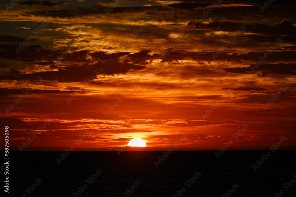 Fototapeta premium Sunrise on the Atlantic Ocean. The sunlight cresting the cloudy horizon...painted in reds, oranges and yellow.