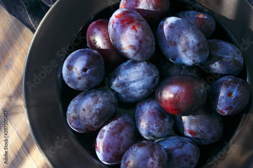 Fresh blue plums in black plate