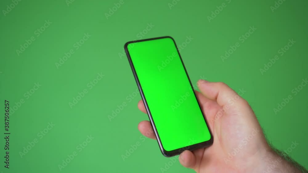 man hand holding the smartphone on green screen chroma key background. Mobile phone mock-up for your product. man hand holding the smartphone on green screen chroma key background. Mobile phone mock-up for your product.