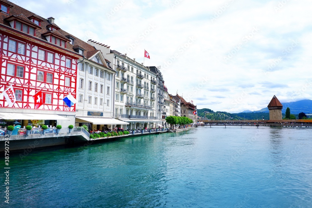 Lucerne, Switzerland - June 15, 2019 : City centre of old town Lucerne with restaurant, crowd and famous chapel bridge with clear blue crystal river of Lucerne, Vierwaldstattersee, Canton of Lucerne