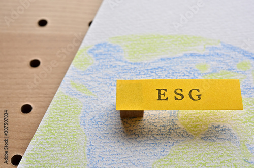 There is a sticky note with the word "ESG" written on top of a sketchbook with an illustration of the earth. It is an acronym that stands for environmental, social and governance.
