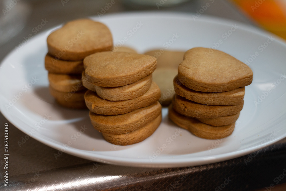 皿の上に積み重ねたハート型のこんがりクッキー。お菓子作り、クッキング、おうち時間 皿の上に積み重ねたハート型のこんがりクッキー。お菓子作り、クッキング、おうち時間