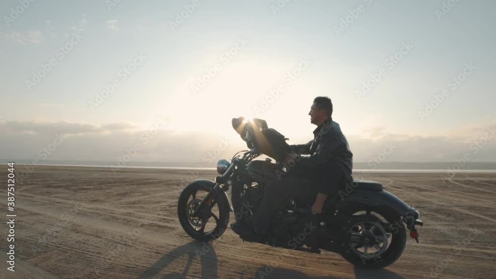 Guy with a girl on a motorcycle in the desert. Couple riding on vintage motorcycle and having a good time at sunset on a dry salt lake. Slow motion shot Guy with a girl on a motorcycle in the desert. Couple riding on vintage motorcycle and having a good time at sunset on a dry salt lake. Slow motion shot