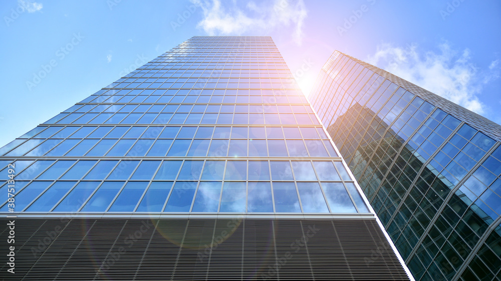 Bottom view of modern office buildings in the business district. Skyscraper glass facades on a bright sunny day with sunbeams in the blue sky. Bottom view of modern office buildings in the business district. Skyscraper glass facades on a bright sunny day with sunbeams in the blue sky.