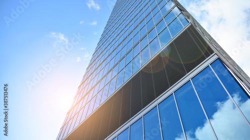 Bottom view of modern office buildings in the business district. Skyscraper glass facades on a bright sunny day with sunbeams in the blue sky.