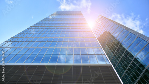 Bottom view of modern office buildings in the business district. Skyscraper glass facades on a bright sunny day with sunbeams in the blue sky.