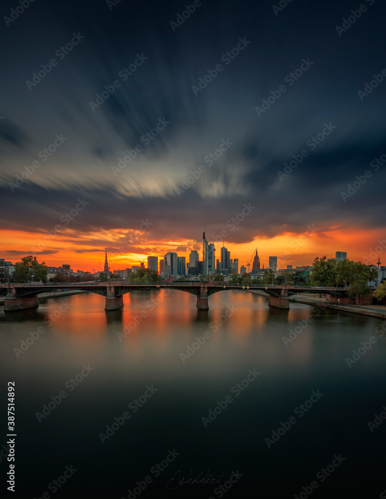Great view of Frankfurt and the skyline. In the evening with backlighting - sunset. A long exposure draws the water softly and gives the picture a great atmosphere
