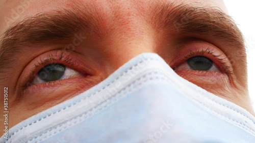 Close-up of irritated eyes of a sick man with a protective face mask photo