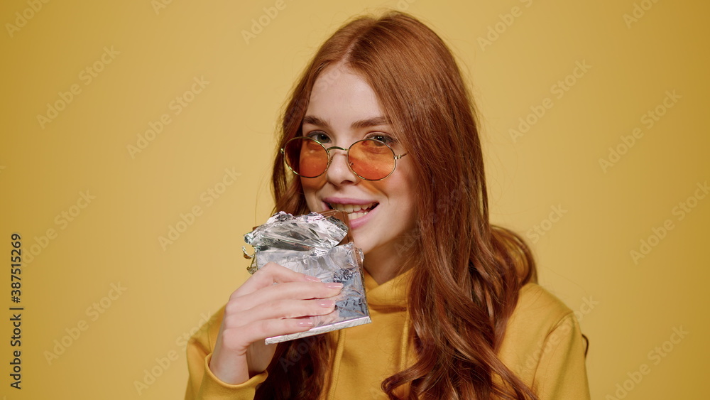Portrait of sexy girl biting chocolate bar indoors. Redhead woman winking Portrait of sexy girl biting chocolate bar indoors. Redhead woman winking