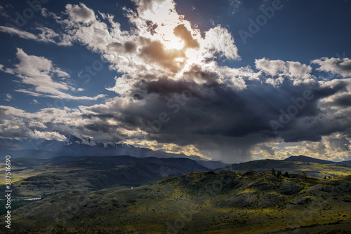 Majestic landscape. Rain clouds snowy peaks beautiful sky with sun rays. Storm sweeps over Kurai steppe in Altai mountains. Harsh climate of Siberia.