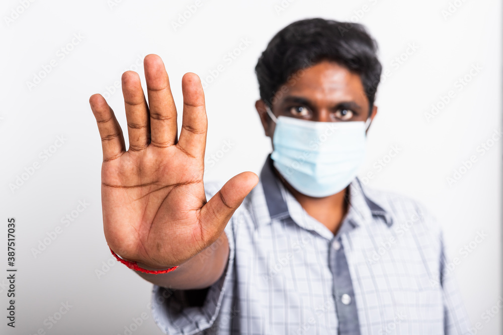 Closeup Asian handsome black man wearing surgical hygienic protective cloth face mask against coronavirus and raising hand stop sign, studio shot isolated white background, COVID-19 medical concept Closeup Asian handsome black man wearing surgical hygienic protective cloth face mask against coronavirus and raising hand stop sign, studio shot isolated white background, COVID-19 medical concept
