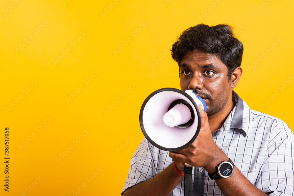 Asian happy portrait young black woman standing to make announcement message shouting screaming in megaphone, studio shot isolated on yellow background with copy space Asian happy portrait young black woman standing to make announcement message shouting screaming in megaphone, studio shot isolated on yellow background with copy space