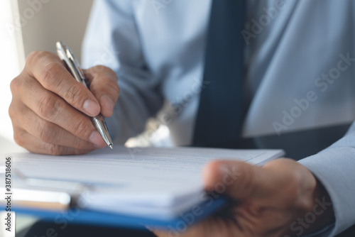 Businessman with pen in hand signing business document working in office