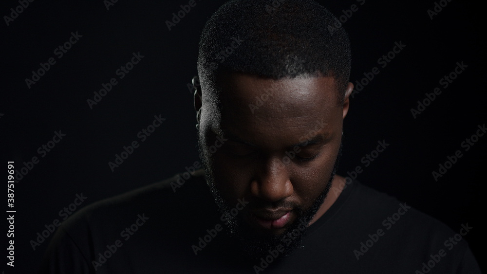 Surprised afro man staring at lens indoors. African guy raising head in studio