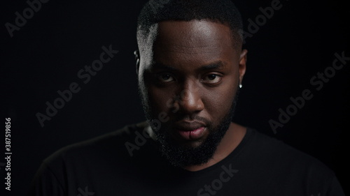 Serious african man posing on black background. Portrait of afro guy in studio