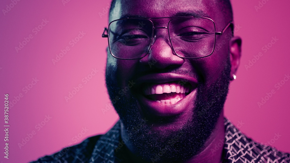 Fototapeta African american man laughing in studio. Natural male person smiling indoors