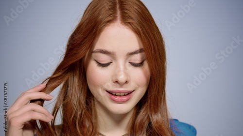 Attractive redhead girl impressing somebody in studio. Woman flirting indoors