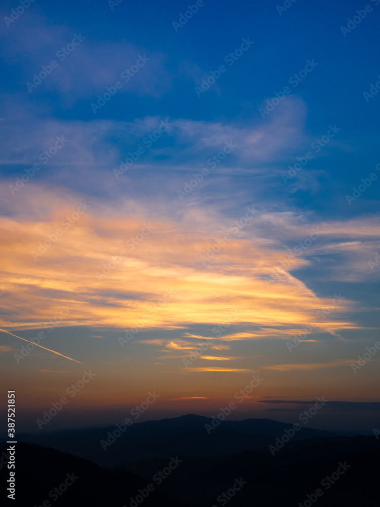 Orange clouds and blue sky at sunset in mountains