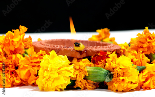 Marigold flowers around Clay Oil Lamp or Diwali Diya, over white background. selective focus photo