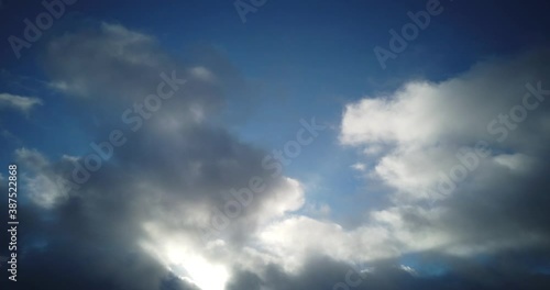 Fast moving time lapse of dark and bright clouds swirling on blue sky