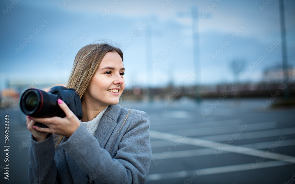 Pretty, young woman taking photos with her professional dslr camera