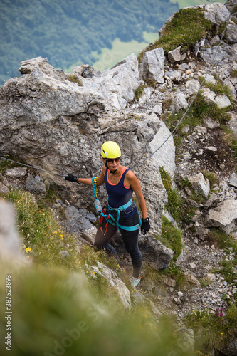 Pretty, female climber on a via ferrata - climbing on a rock in Swiss Alps