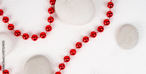 banner for web white sea stones and red beads between them on a white background. substrate, texture, red beautiful bright beads, beauty and style