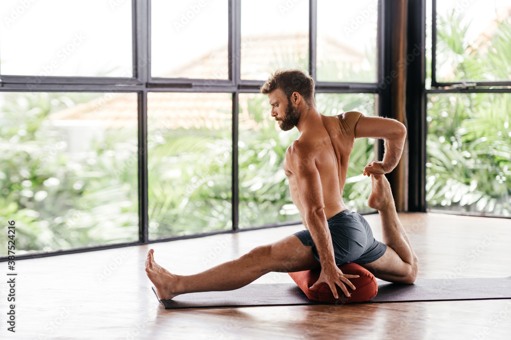 Yoga men workout in studio, training in front of a window Yoga men workout in studio, training in front of a window