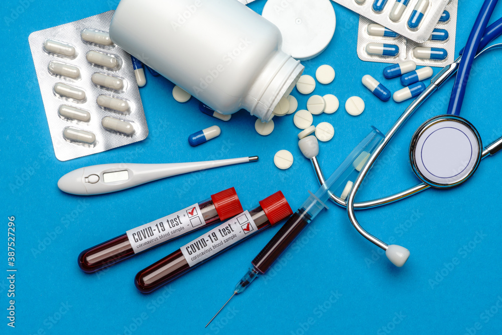 Stethoscope, syringe, thermometer, blood test tube and can of pills on blue background top view with copy space Stethoscope, syringe, thermometer, blood test tube and can of pills on blue background top view with copy space