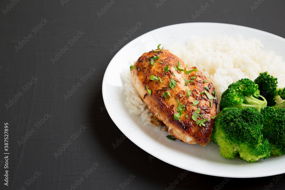Homemade Chicken Breast, Rice and Broccoli on a white plate on a black surface, side view. Space for text. Homemade Chicken Breast, Rice and Broccoli on a white plate on a black surface, side view. Space for text.