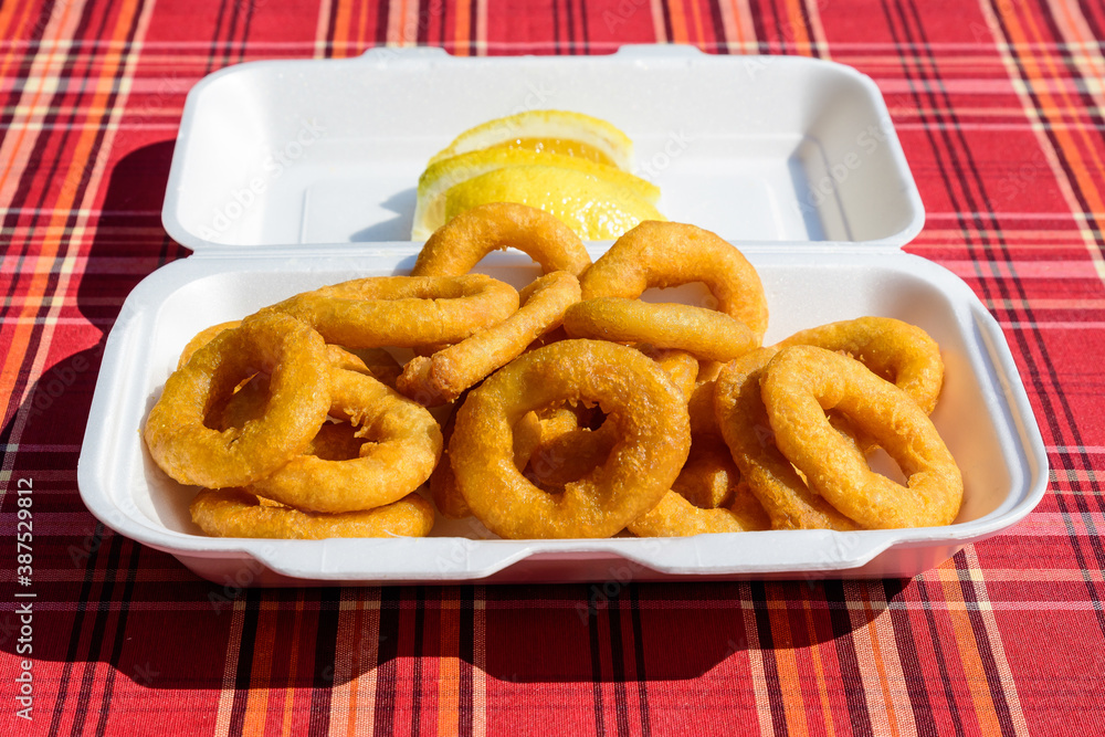 Large group of freshly fried calamari and onion rings on display for sale at a street food festival, ready to eat healthy seafood, beautiful orange monochrome outdoor background. Large group of freshly fried calamari and onion rings on display for sale at a street food festival, ready to eat healthy seafood, beautiful orange monochrome outdoor background.