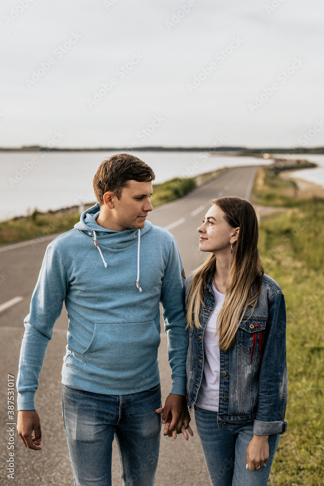 Portrait of romantic couple look to each other and walking along the shore with mountains Portrait of romantic couple look to each other and walking along the shore with mountains