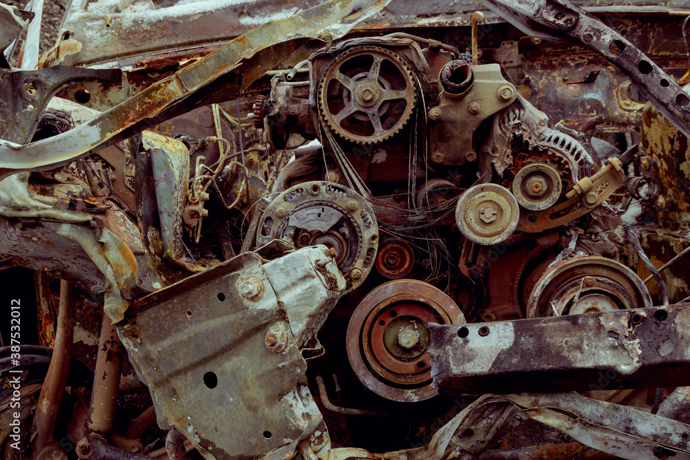 A burnt-out car after a severe accident at a scrap yard, a destroyed car engine close-up.