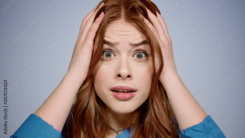 Ginger woman taking head in hands indoors. Stressed girl posing in studio Ginger woman taking head in hands indoors. Stressed girl posing in studio