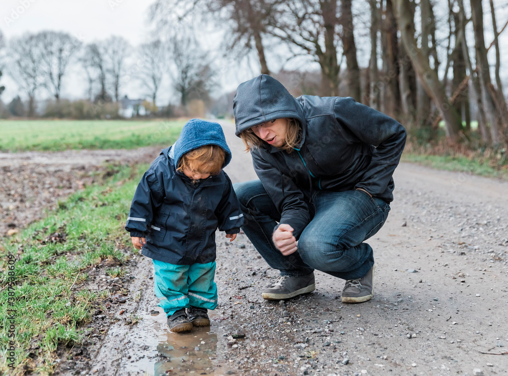 Toddler girl with young man crouching on footpath Toddler girl with young man crouching on footpath