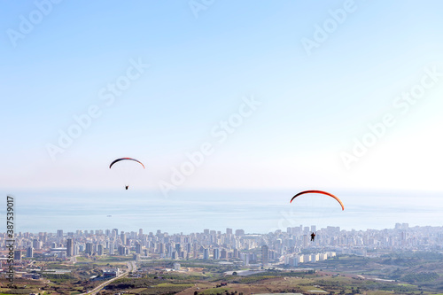 The paragliders are flying with paragliding on the city.