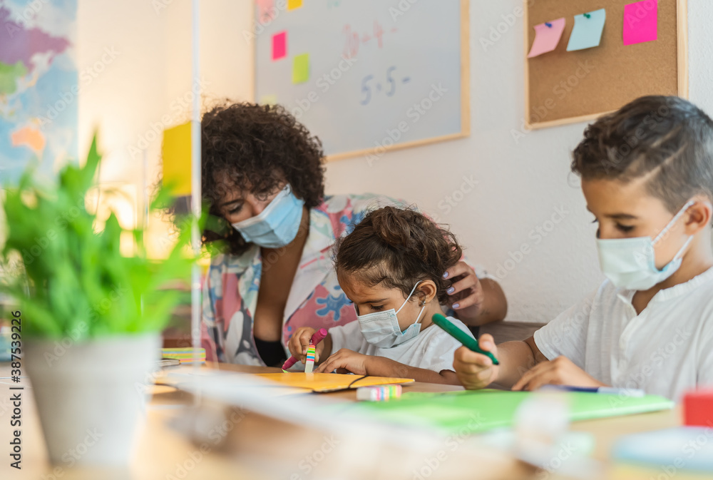 Teacher with children wearing face mask in preschool classroom during corona virus pandemic - Healthcare and education concept Teacher with children wearing face mask in preschool classroom during corona virus pandemic - Healthcare and education concept