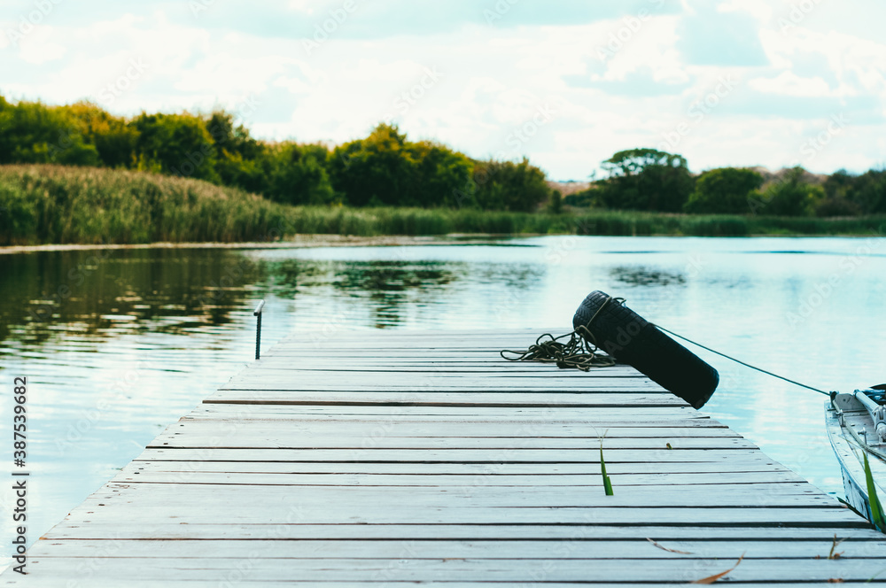 Obraz premium beautiful lanscape of wooden rustic old pier in front of green reeds and trees on river 