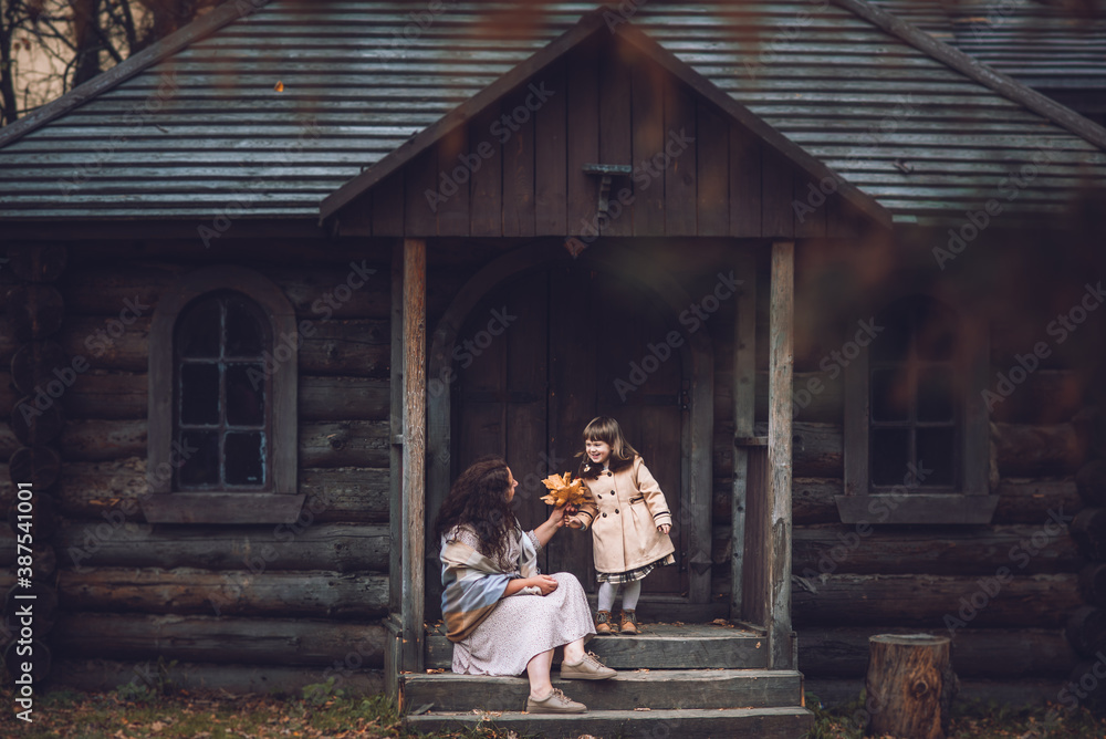 little girl in a coat at a wooden house