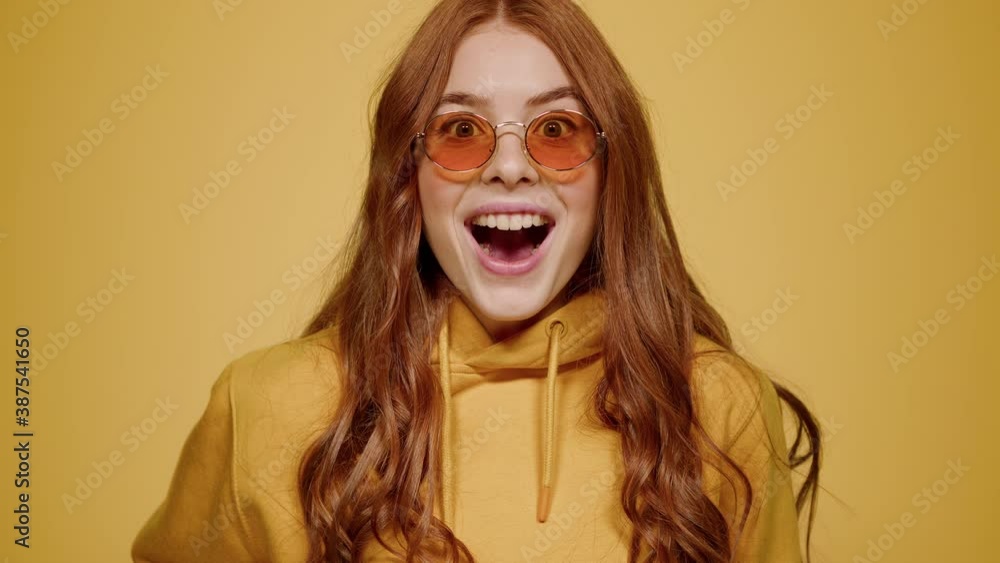 Euphoric girl making hand gesture on orange background. Woman acting indoors Euphoric girl making hand gesture on orange background. Woman acting indoors