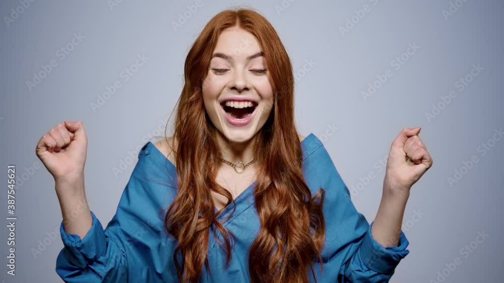 Euphoric girl making winner gestures in studio. Woman rejoicing indoors Euphoric girl making winner gestures in studio. Woman rejoicing indoors