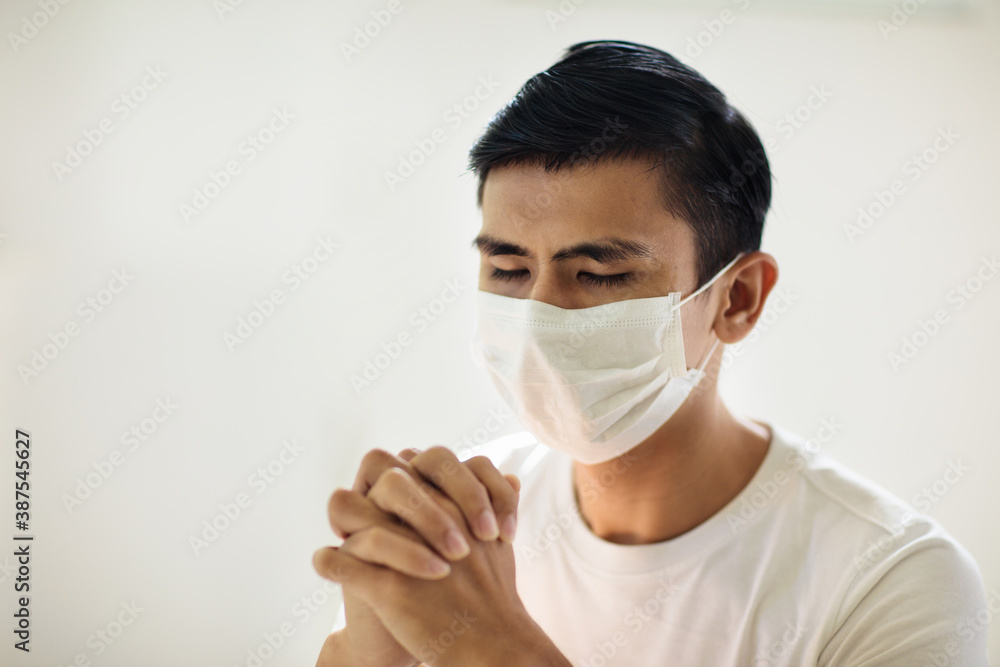 Asian man in face mask praying for