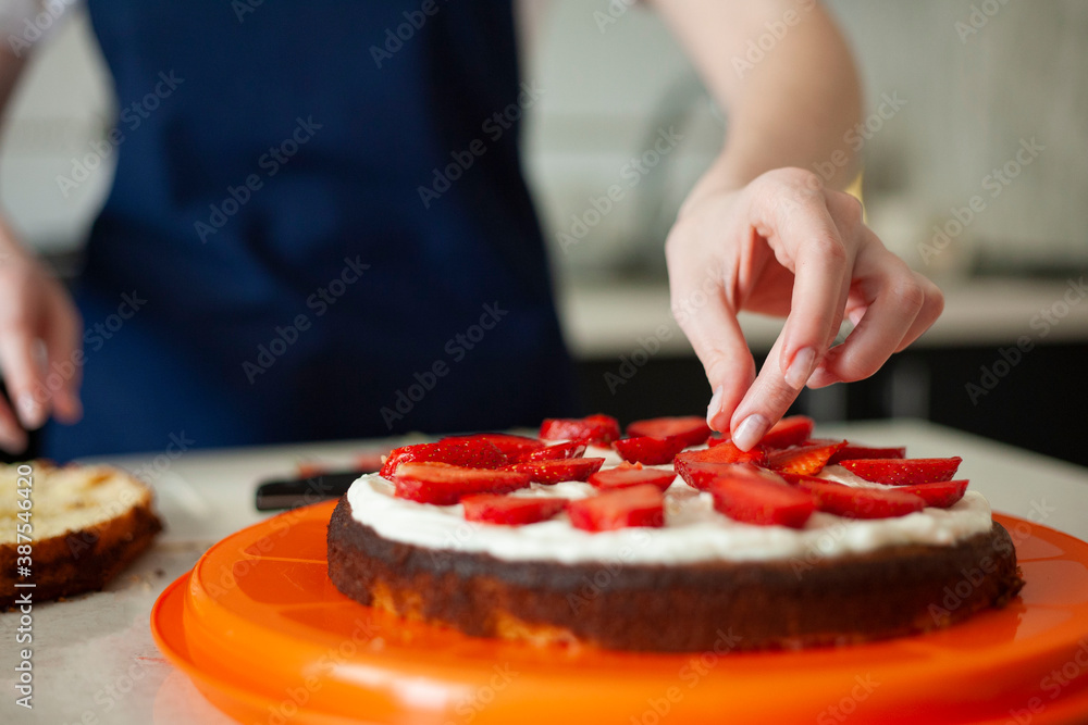 young woman decorates a birthday cake with strawberries. cake decoration.