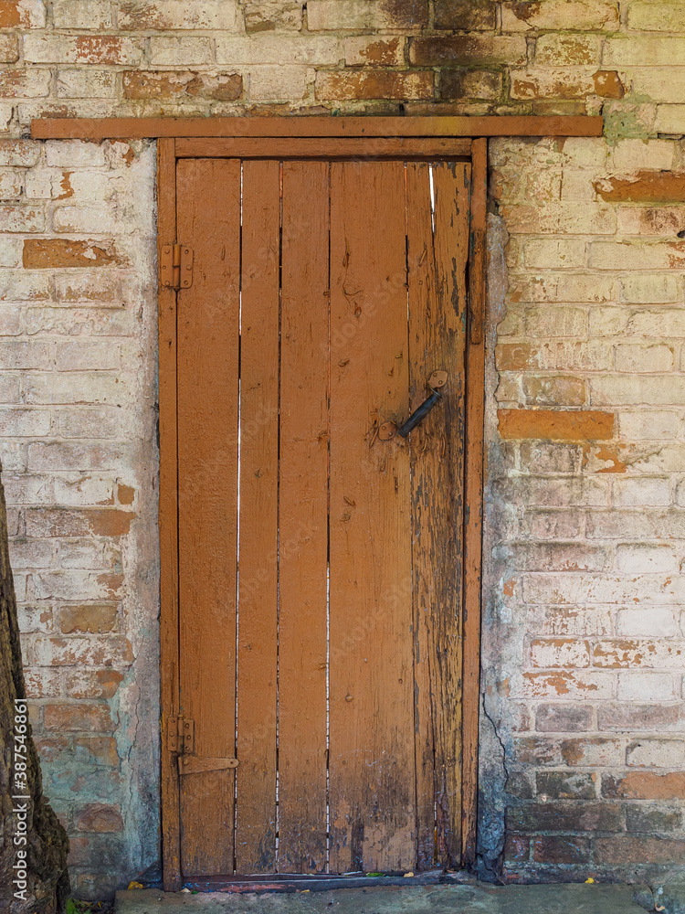 Naklejka premium brown wooden door in a vintage brick wall