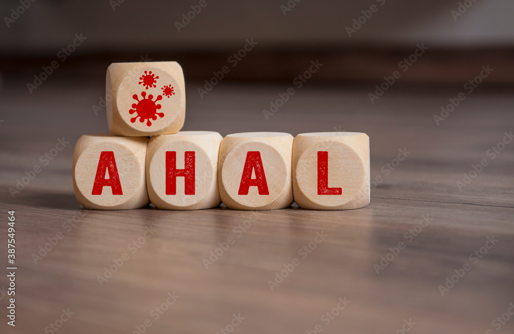 Cubes and dice with covid-19 corona virus and the german acronym for AHA - Abstand, Hygiene, Alltagsmaske on wooden background